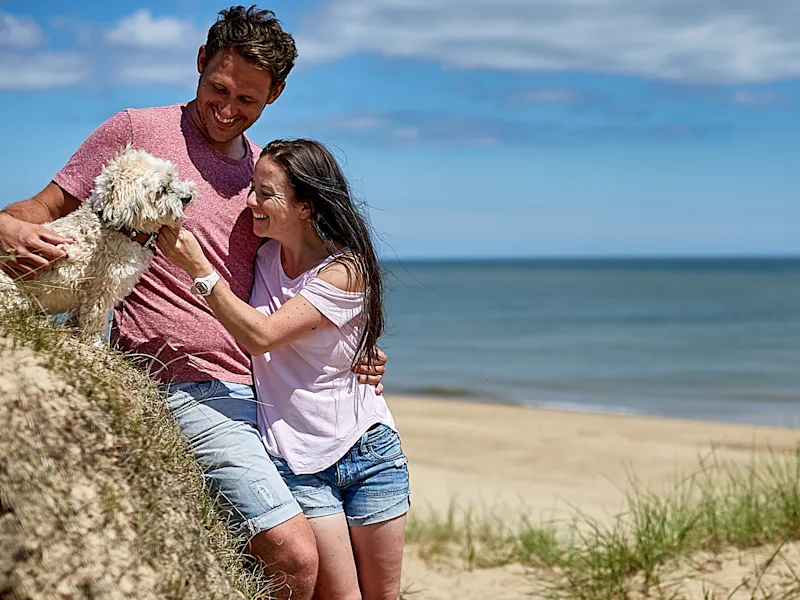 Couple & dog on the beach at Hemsby Beach Holiday Park (HEMS) in Hemsby, Great Yarmouth, Norfolk, UK