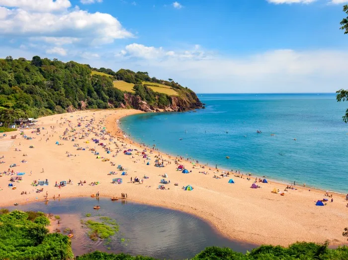 A sunny seascape with people enjoying the beach at Blackpool sands near Dartmouth in Devon