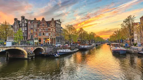 Zonsondergang boven de skyline van Amsterdam aan de grachten, Nederland.