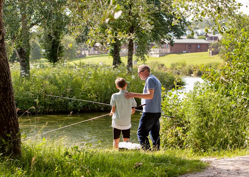 Father and son fishing at White Acres holiday park (WHIA) in Newquay, Cornwall, UK