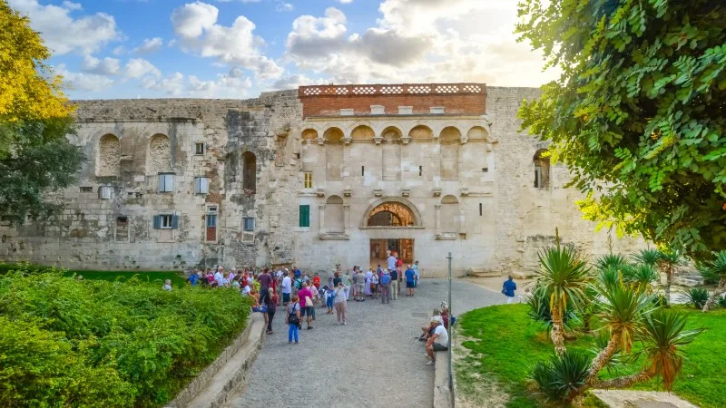 Tourists gather in tour groups outside the ancient Golden Gate to the Diocletian's Palace section of Old Town Split, Croatia in early autumn.