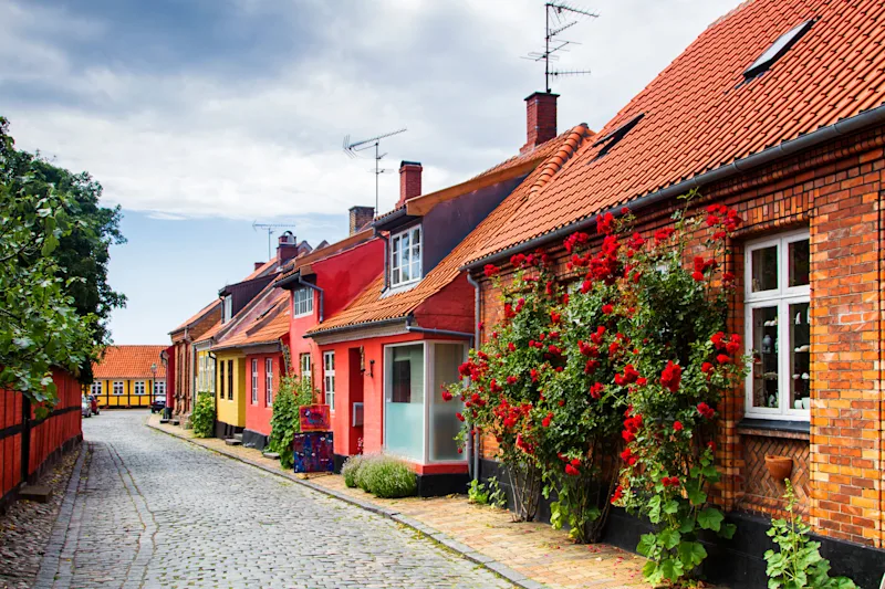 Straße mit Kopfsteinpflaster und kleinen, bunten Häusern auf Bornholm.