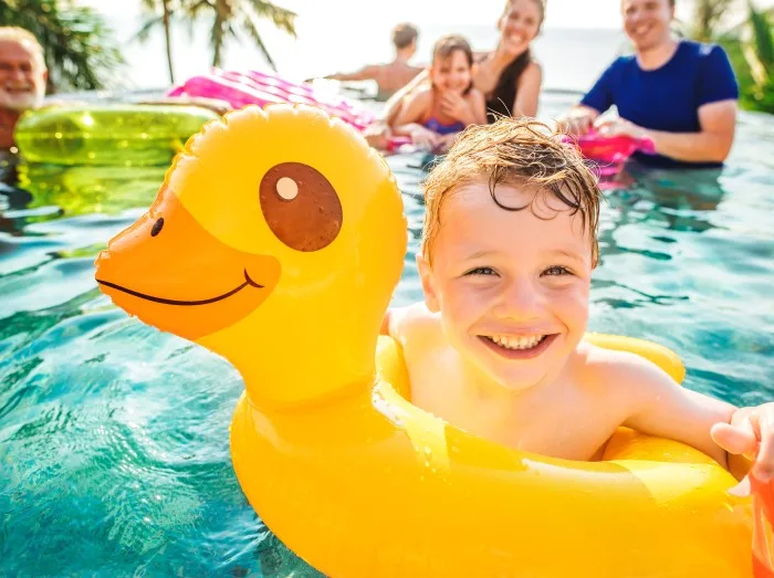 Boy swimming in a pool with family