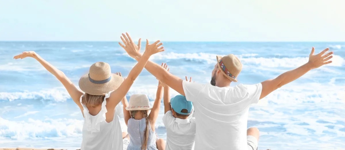 Happy family sitting on sea beach at resort