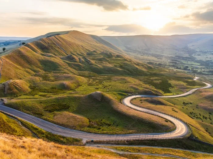 Beautiful winding road and hills at sunset in the Peak District 