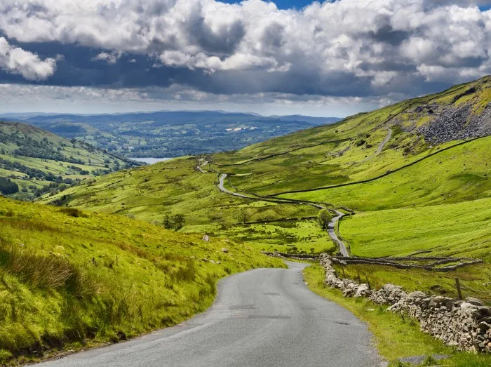 The Struggle road at Kirkstone Pass leading to Windermere lake Ambleside with Snarker Pike of Red Screes mountain on right in Lake District 