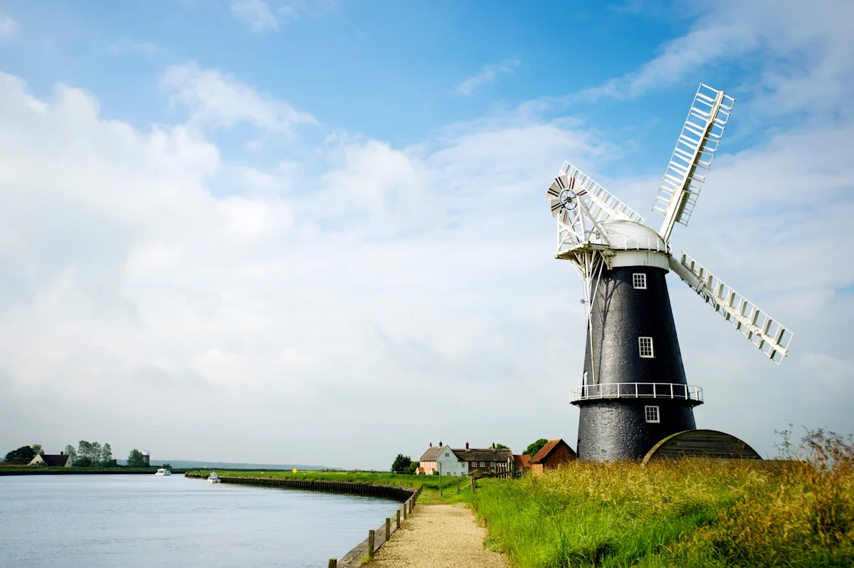 Windmill in the countryside by a river in the Norfolk Broads, England, UK