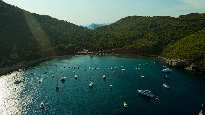 Blick auf den Strand Sunj Beach auf der Insel Lapad, in der Nähe von Dubrovnik in Kroatien. Bucht mit Wald im Hintergrund und Booten auf dem Meer.