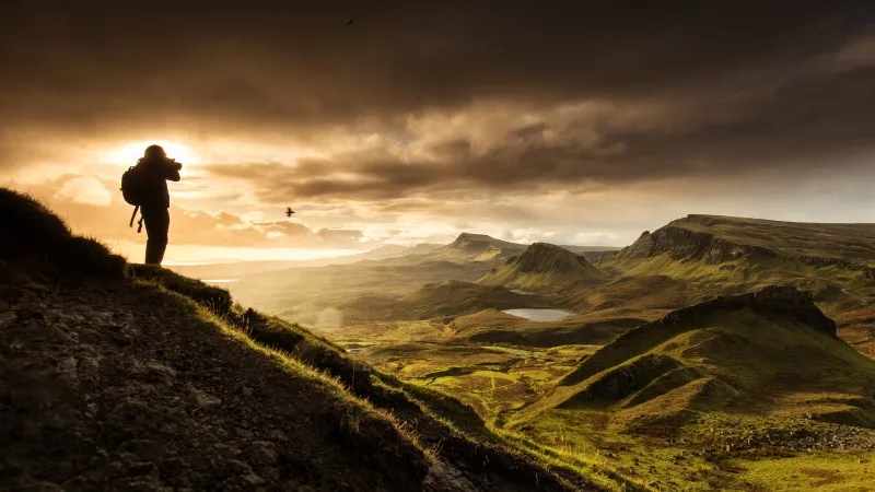 Silhoutte of photographer shooting scenic view of Quiraing mountains in Isle of Skye, Scottish highlands