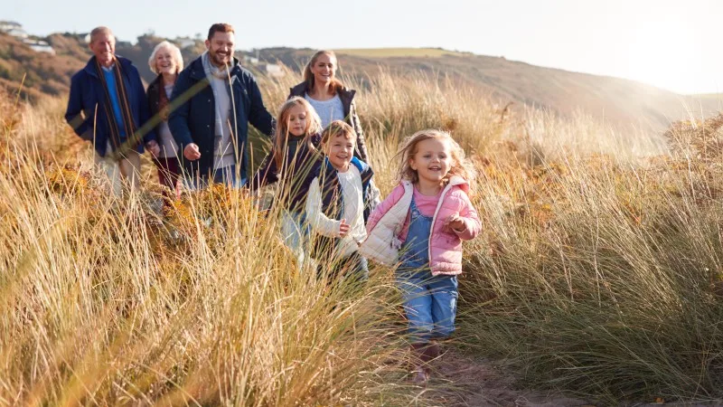 Multi-Generation Family Walking Along Path Through Sand Dunes Together