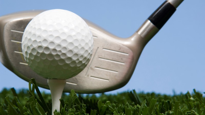 golf ball on tee on grass with driver