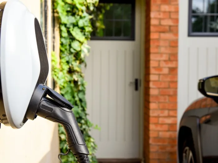 Electric car plugged in to charge outside home with power cable