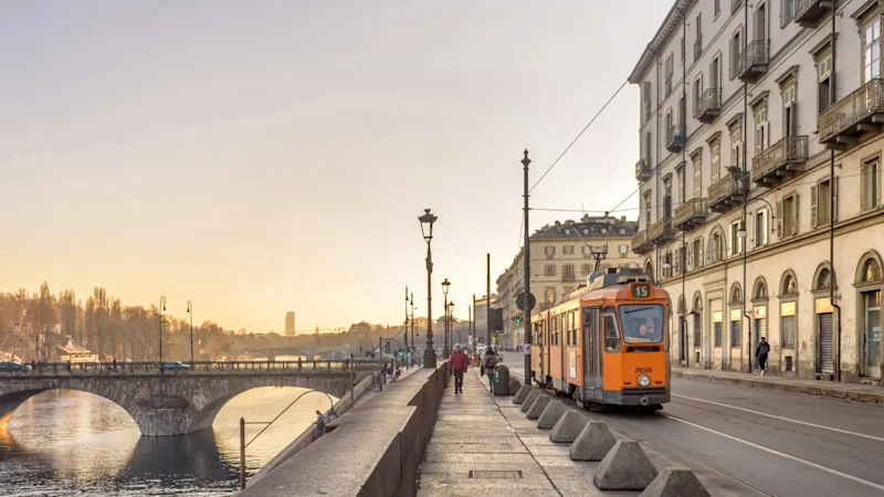 Straßenbahn in Turin mit der historischen Stadt im Hintergrund.