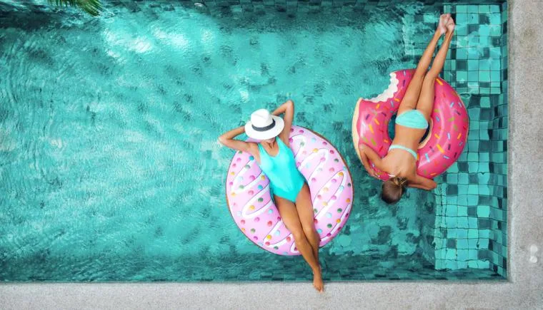 Two women relaxing in a holiday home with a private pool