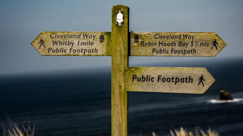 Wooden signpost showing Cleveland Way directions to Whitby and Robin Hoods Bay, North York Moors National Park, Whitby, 