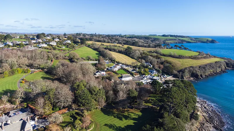 View of a village next to the rocky coastline of Helston passage on a sunny afternoon