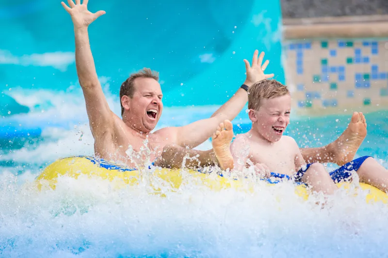 Father and son having fun on a waterpark slide