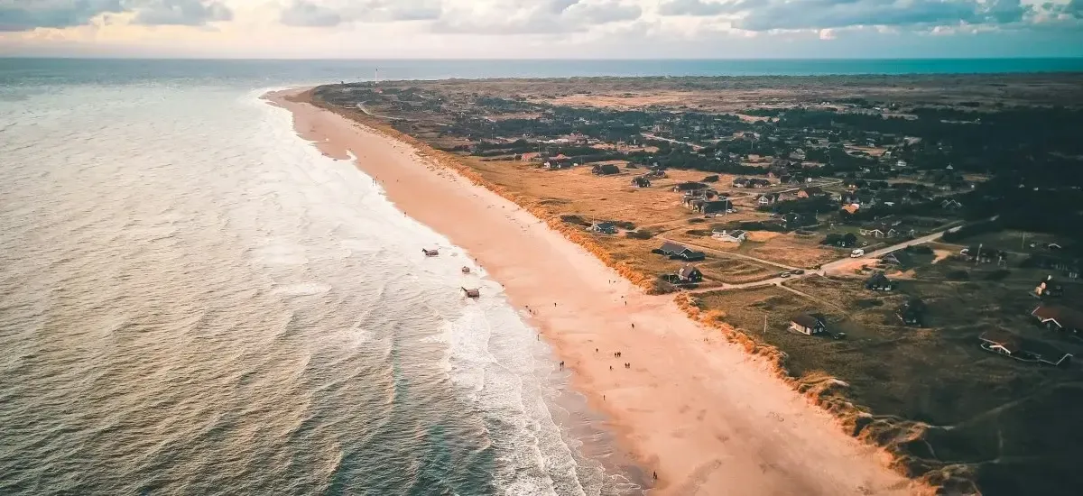 Blåvand Strand set fra luften i rødligt solnedgangslys.