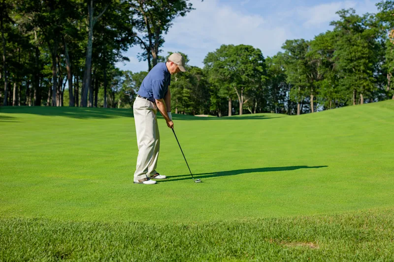 Golfer gets ready to hit onto a green on a sunny afternoon