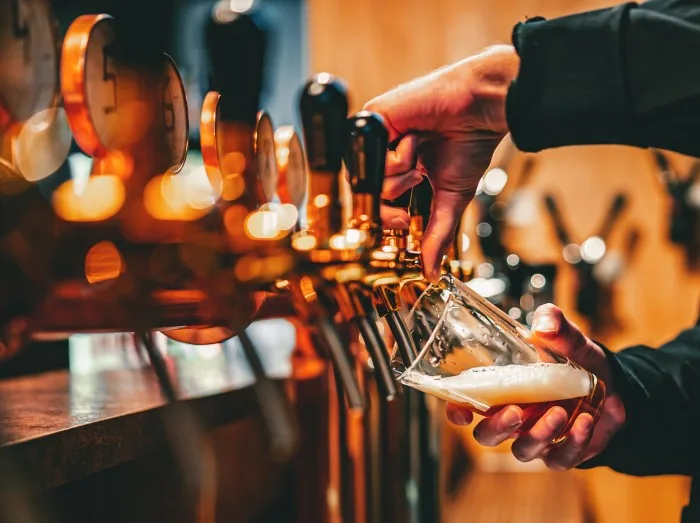 bartender hand at beer tap pouring a draught beer in glass serving in a bar or pub