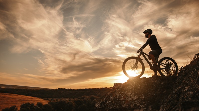 Man on mountain bike against sundown sky