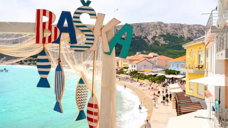 Large BAŠKA sign at the entrance to the beach decorated for Fishermen’s Days, a local celebration in Krk Island