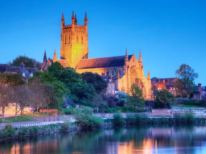 Worcester Cathedral floodlit on a spring evening and reflected in the River Severn.