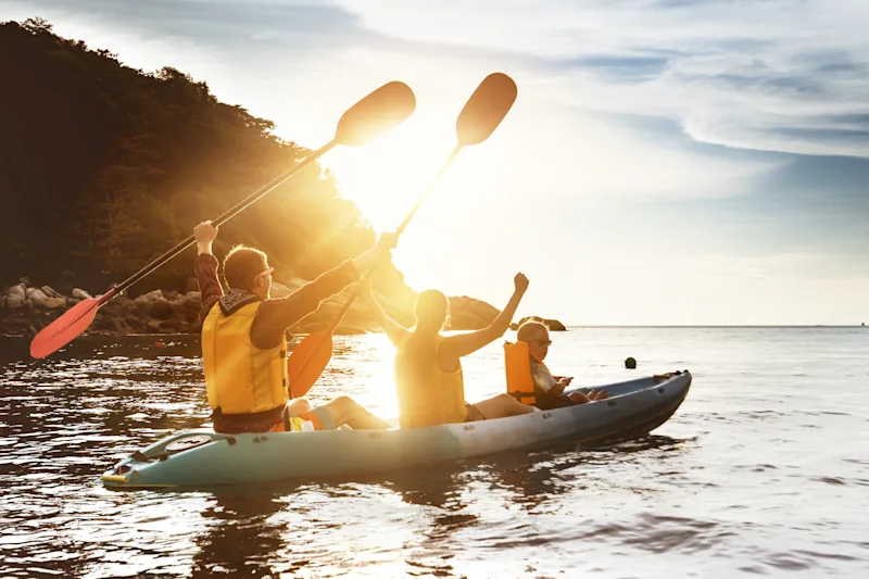 Family sea kayaking at sunset