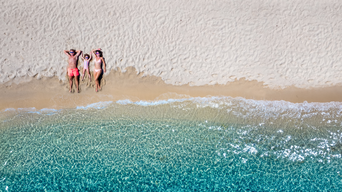 Eine Familie liegt am Meer im Sand.