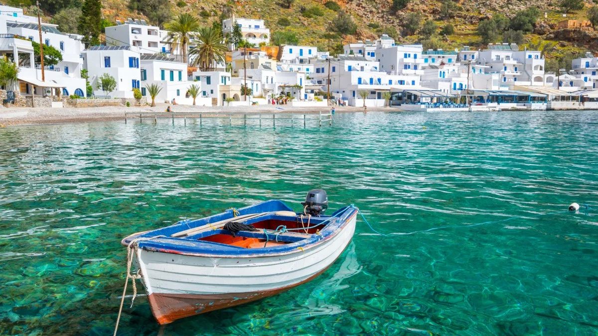 Fishing boat and the scenic greek village of Loutro in Crete,