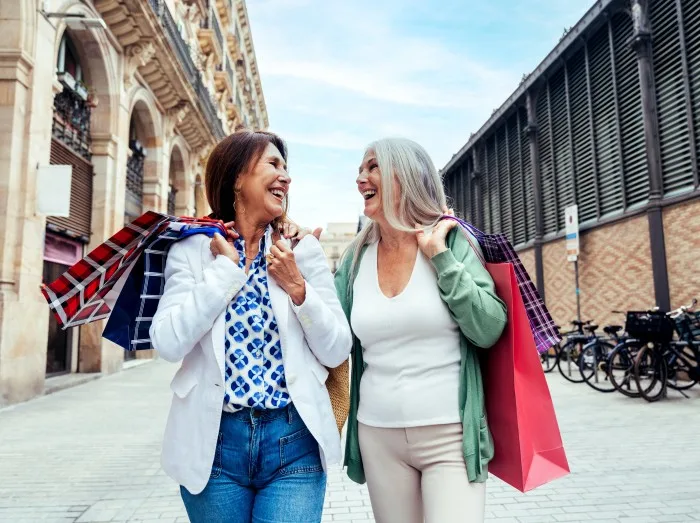 Beautiful senior women meeting outdoors in the city - Two mature female adults friends bonding and having fun while shopping outdoors