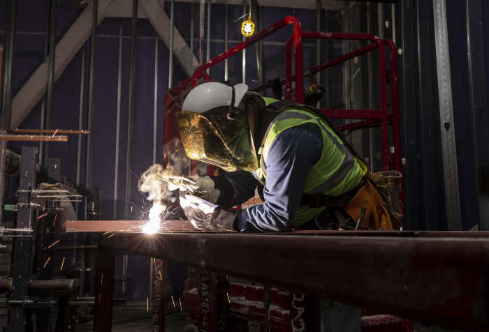 Image shows a welder in full protective equipment working in a shop setting