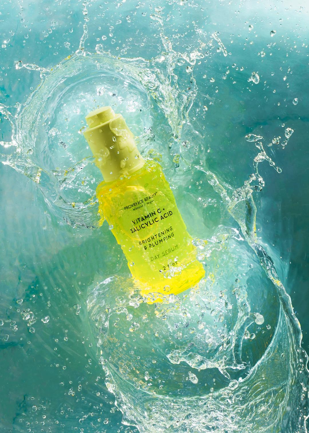 A yellow bottle of facial cleanser splashing into water