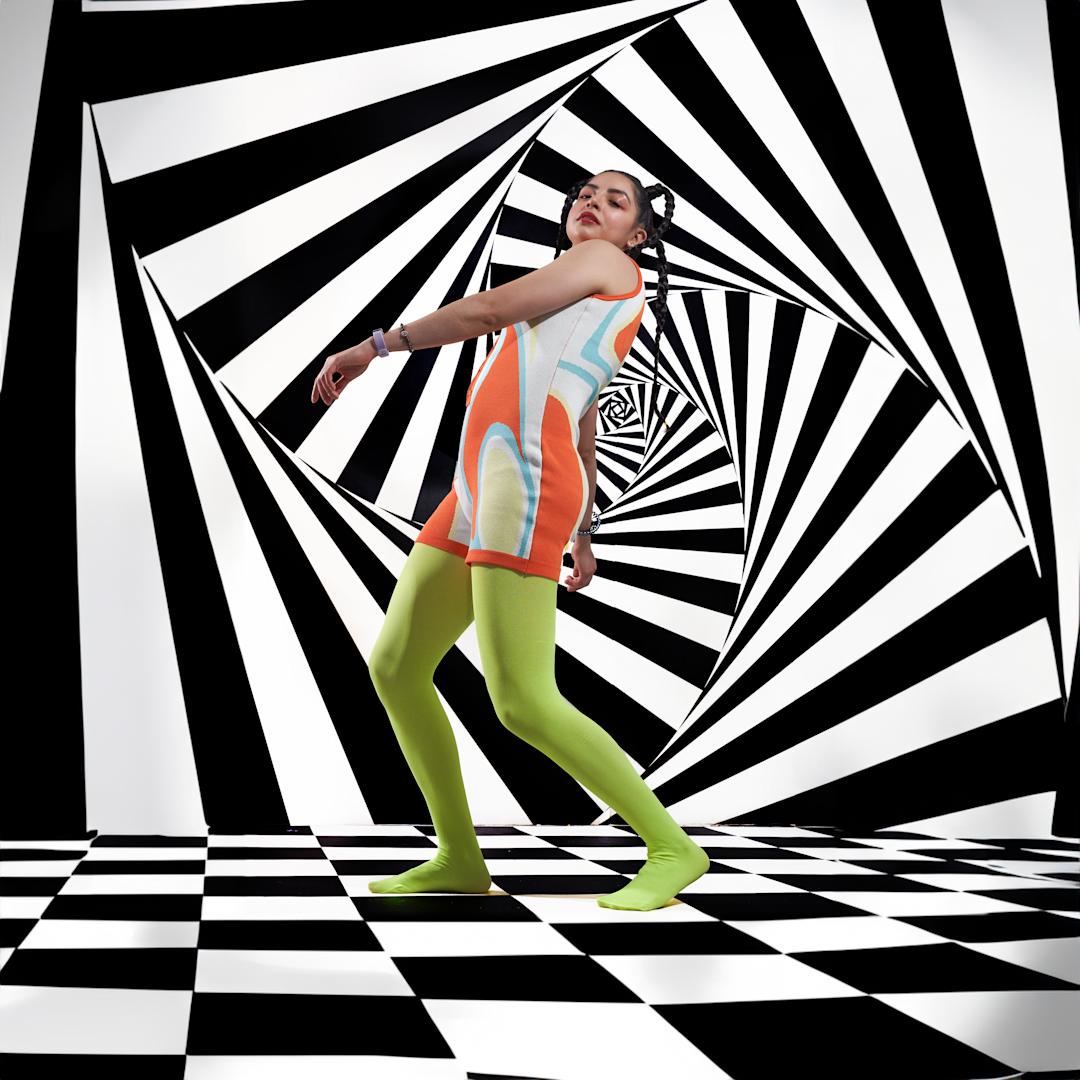 a woman in green tights against a black and white patterned wall