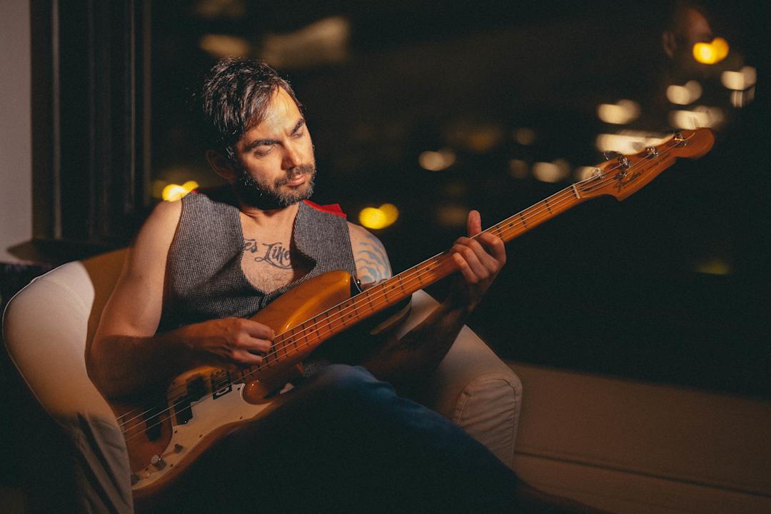 man with a bass guitar sitting in a chair
