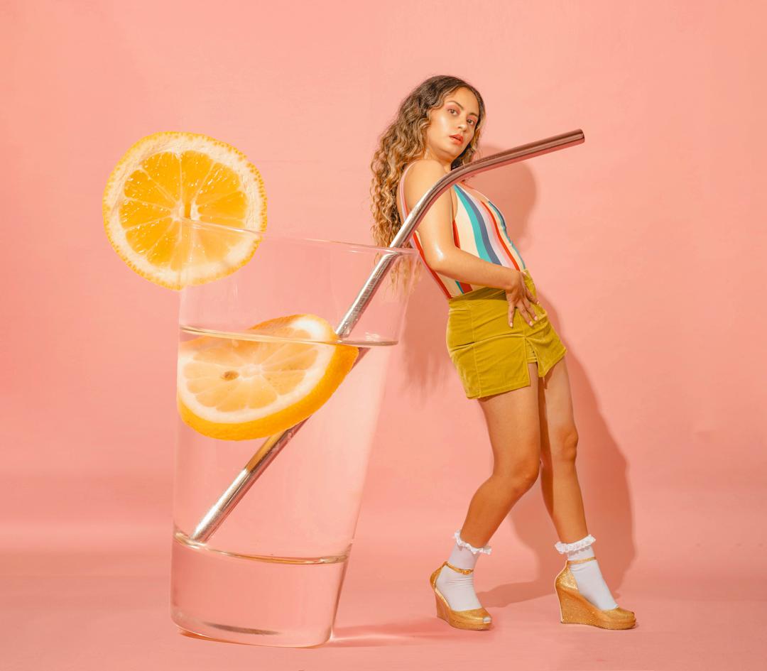 A woman leaning on a giant glass of lemonade