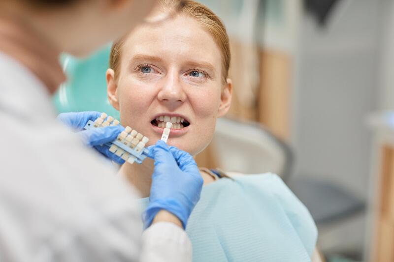 Femme chez le dentiste lors d'un appariement des couleurs de couronnes dentaires