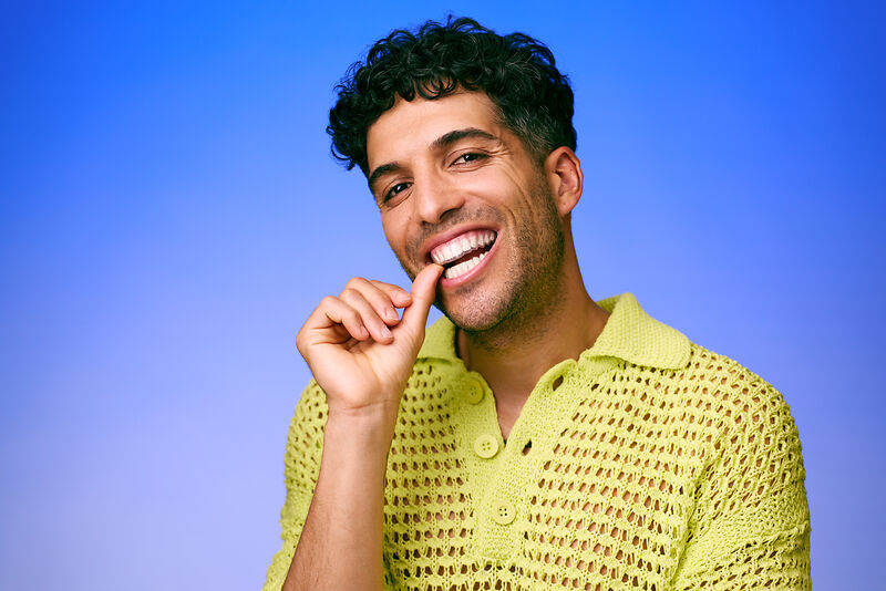 [CRO] Man - Brunette - Curly hair - Smile - Finger on mouth - Looking left - Green - Knitting - T-shirt - Blue - Gradient - Background - Desktop