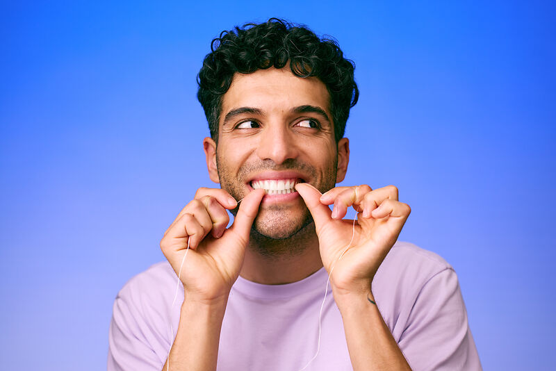 [CRO] Man - Brunette - Curly hair - Dental floss - Looking left - Lilac - T-shirt - Blue - Gradient - Background - Desktop