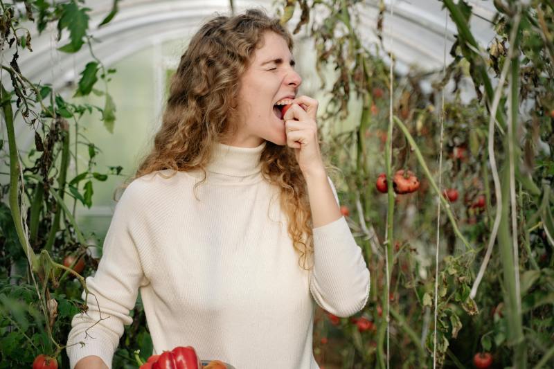 Frau, die in ein Stück Obst beißt @pexels by yankrukov