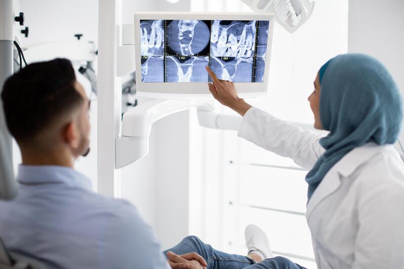Dentiste montrant un scan des dents pour un traitement de la racine dentaire
