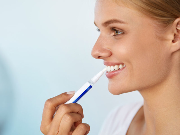 Mujer blanqueandose los dientes en casa