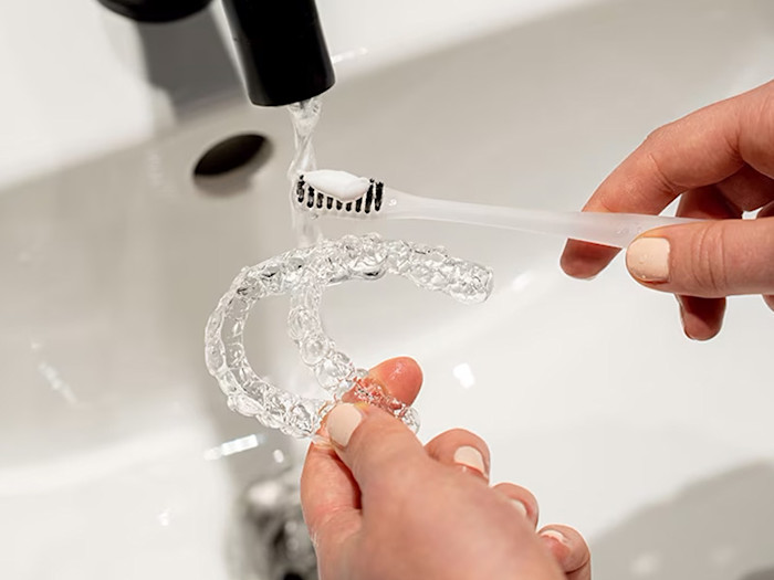 Cepillo de dientes y alineadores dentales debajo de un grifo