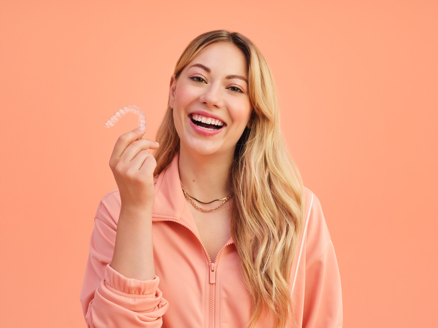 Femme souriant et tenant des aligneurs dentaires transparents dans la main