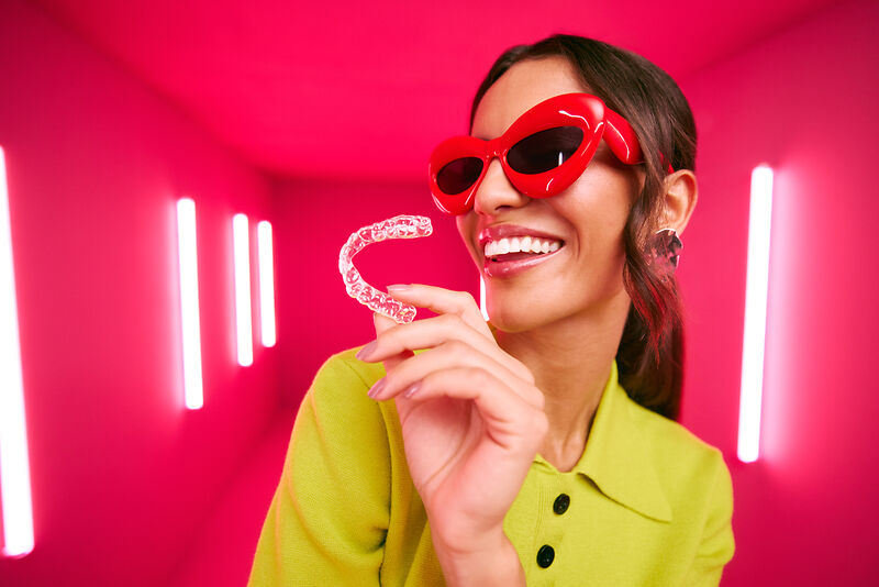 [CRO] Women - Brunette - Green - Shirt - Red Glasses - Aligners - Pink - Light - Background - Desktop