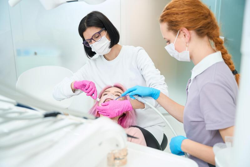 Dentista e igienista effettuano pulizia dentale professionale su paziente