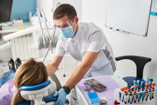 Odontólogo cauteloso realizando un tratamiento dental en mujer