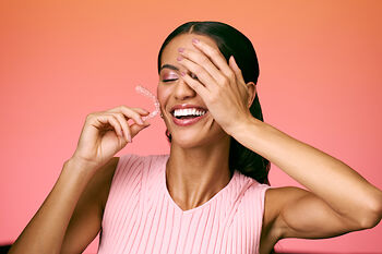 [CRO] Women - Brunette - Left Perfil - Hand on Face - Aligner - Smile - Orange - Gradient - Background - Mobile