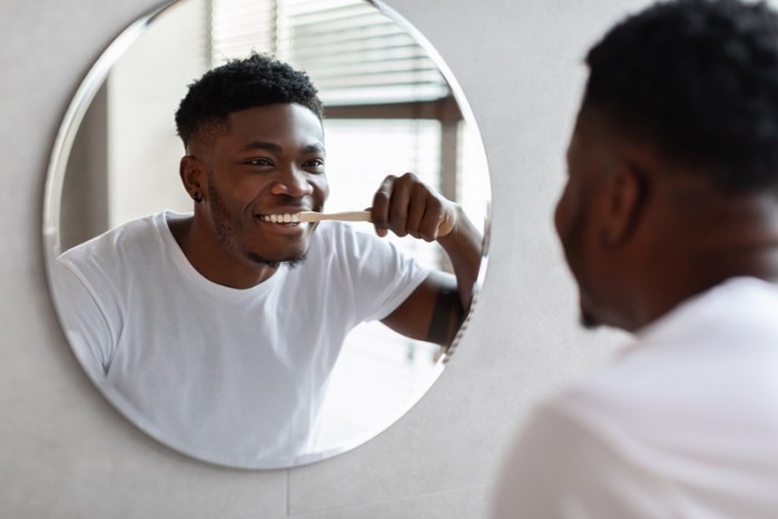 Mann lächelt im Spiegel und zeigt seine Zähne