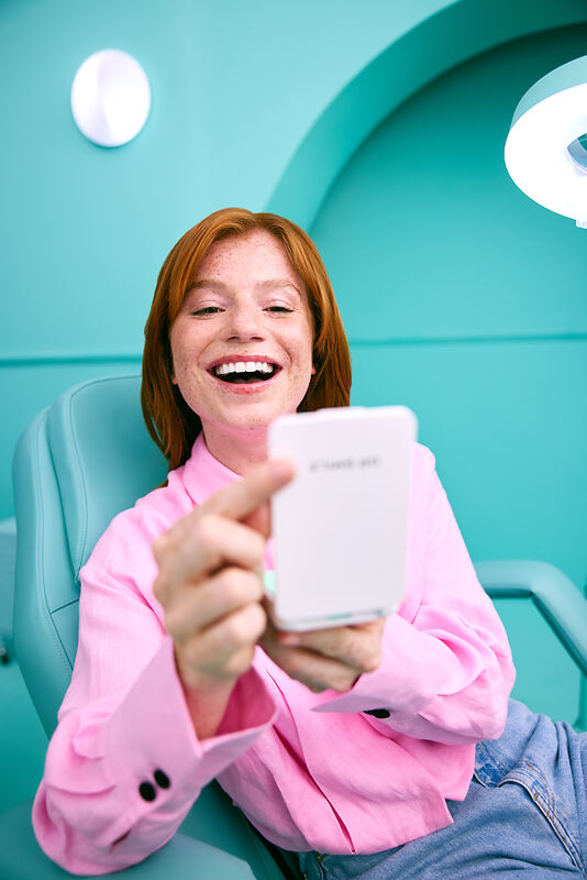 [CRO] Woman - Ginger - Case - Pink shirt - Looking down - Freckles - Blue - Background - Desktop